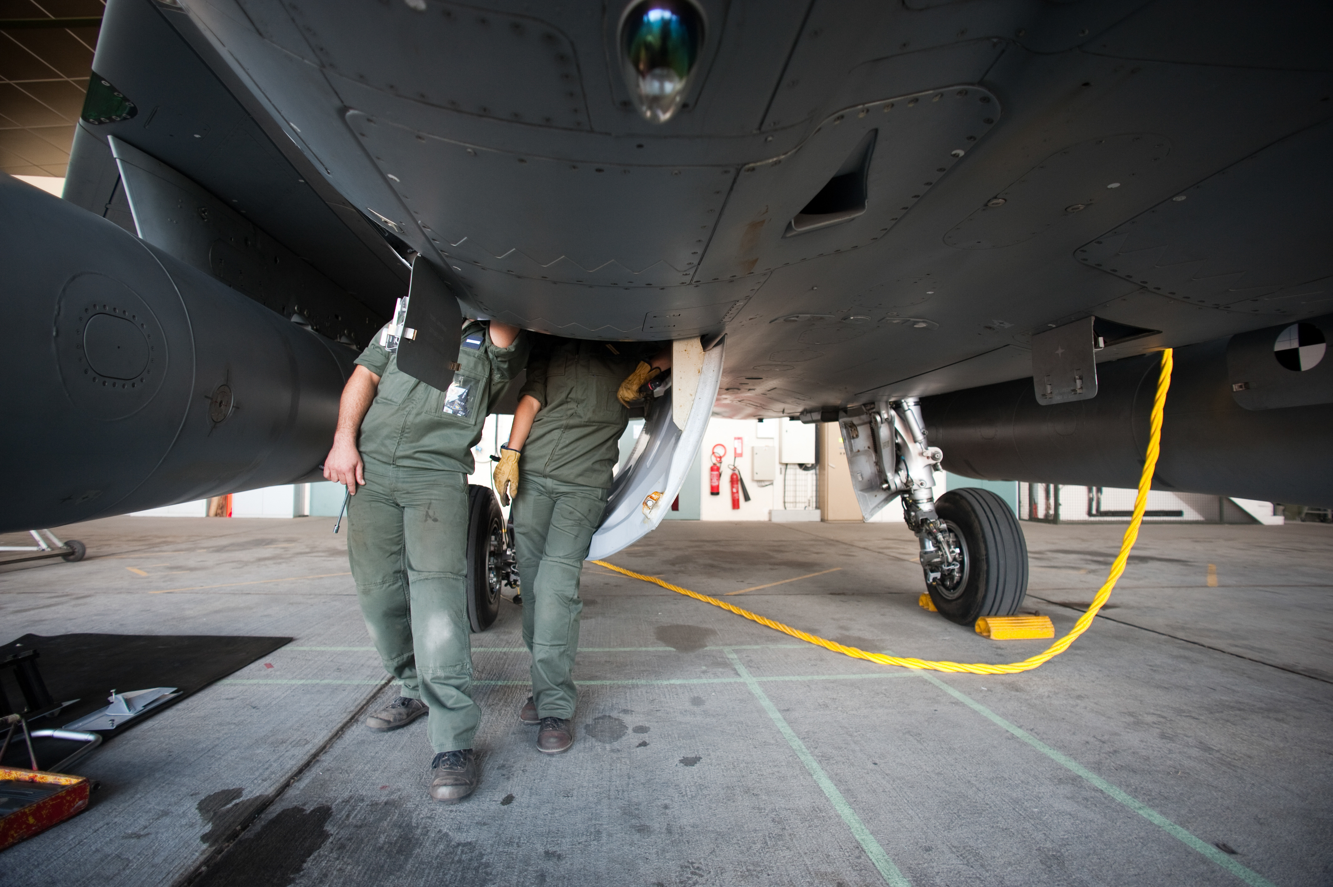 Techniciens de maintenance sous un avion militaire sur base